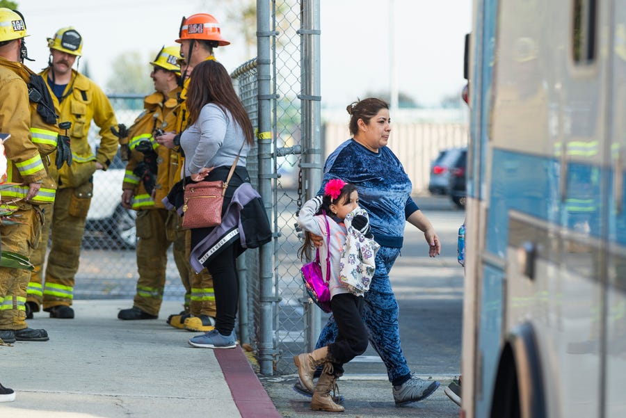 An unidentified girl covers her mouth as she leaves with a relative the Park Avenue Elementary school in Cudahy, Calif., Tuesday, Jan. 14, 2020.