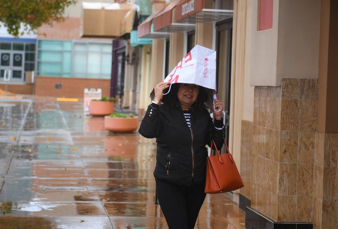 Alicia Calderon uses a Macy's paper bag to shield herself from the rain on Jan. 16, 2020.
