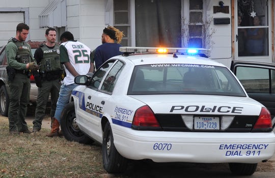 Wichita Falls police question possible suspects during a SWAT search warrant, Wednesday.