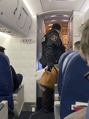 Police remove bags from a flight at Detroit Metro Airport on Thursday, Jan. 16, 2020 during a delay over concerns with a WiFi hot spot name.
