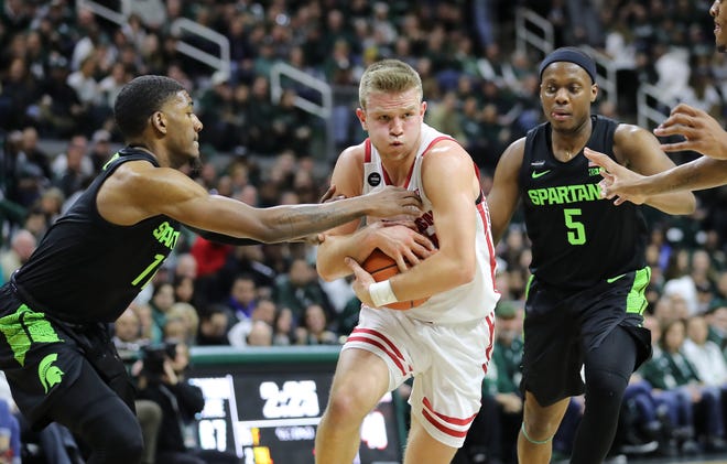 Wisconsin's Brad Davison drives to the basket and draws a foul from Michigan State's Aaron Henry (11)  at the Breslin Center on Friday night.