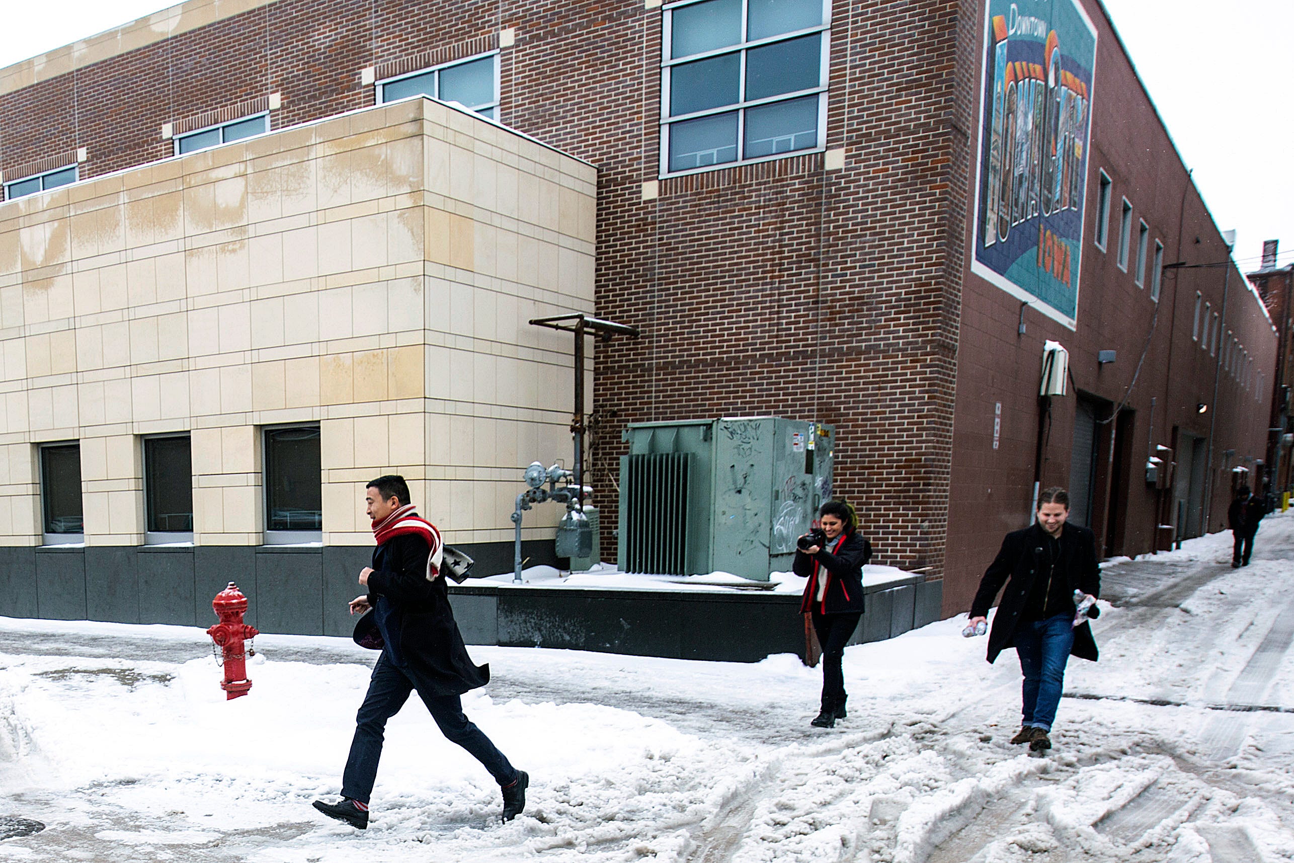 2:34 p.m., Iowa City — Andrew Yang jogs across the street through a bank of snow toward his campaign bus after speaking at a town hall at the Englert Theatre. The event was his first in a bus tour across Iowa leading up to the caucuses.