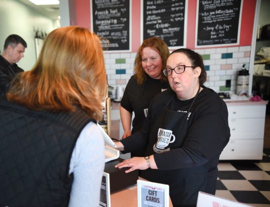 Christina Victor (center), manager, Anastasia and Katie's Coffee Shop and Cafe, works with Danielle Donaldson, who works the front register, as she assists customers.