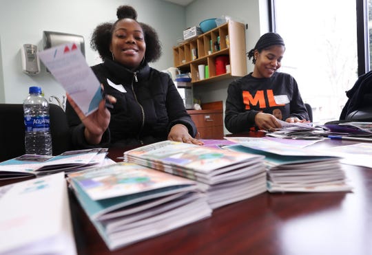 U of L students Tyra Kemp, left, and Spechelle Goodwin fold brochures at the Americana Community Center in Louisville on Monday. They were volunteering as part of the MLK Day of Service.