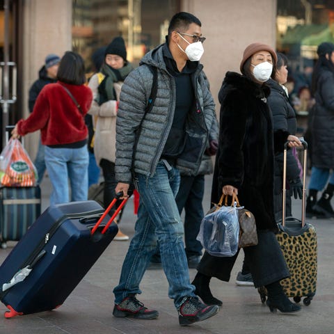 Travelers wear face masks as they walk outside of 