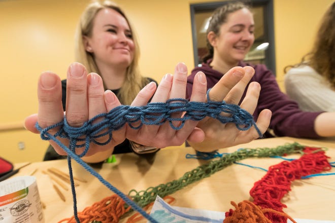 Mary Oblein, left, and Sam Bednarz use their hands for finger-knitting in a math class that incorporates knitting at Carthage College in Kenosha.