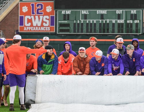 Clemson players help roll up the rain tarp before their first official team Spring practice at Doug Kingsmore Stadium in Clemson Friday, January 24, 2020.