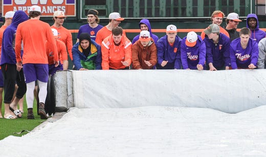 Clemson players help roll up the rain tarp before their first official team Spring practice at Doug Kingsmore Stadium in Clemson Friday, January 24, 2020.