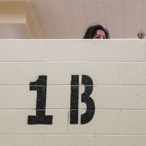 A detainee looks over a dorm wall in a women's hou