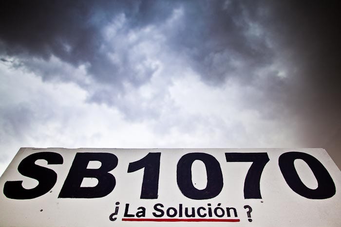 Storm clouds gather over a sign asking if Senate Bill 1070 is the solution to the illegal immigration crisis on July 22, 2010. About 50 people gathered on a street corner in a Hispanic neighborhood in Phoenix to pray the rosary. They were members of a Catholic community that opposed Arizona's tough new immigration law, SB 1070, which required local police officers to check the immigration status of people they suspected of being in the U.S. illegally and required legal immigrants in Arizona to carry their immigration documents with them at all times.