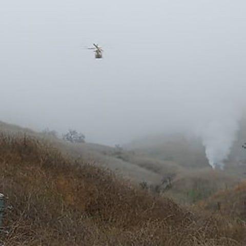 A helicopter flies over the scene of an aircraft c
