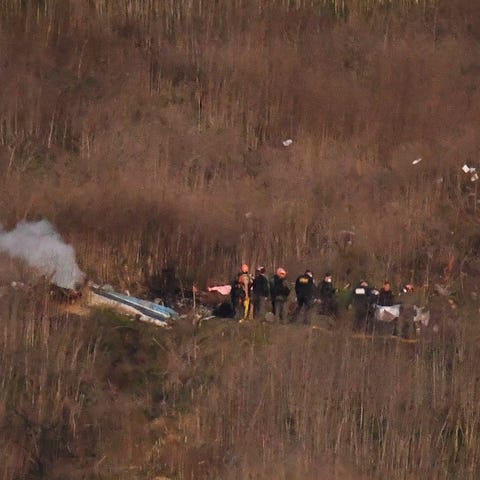 A body is carried from the scene of a helicopter c