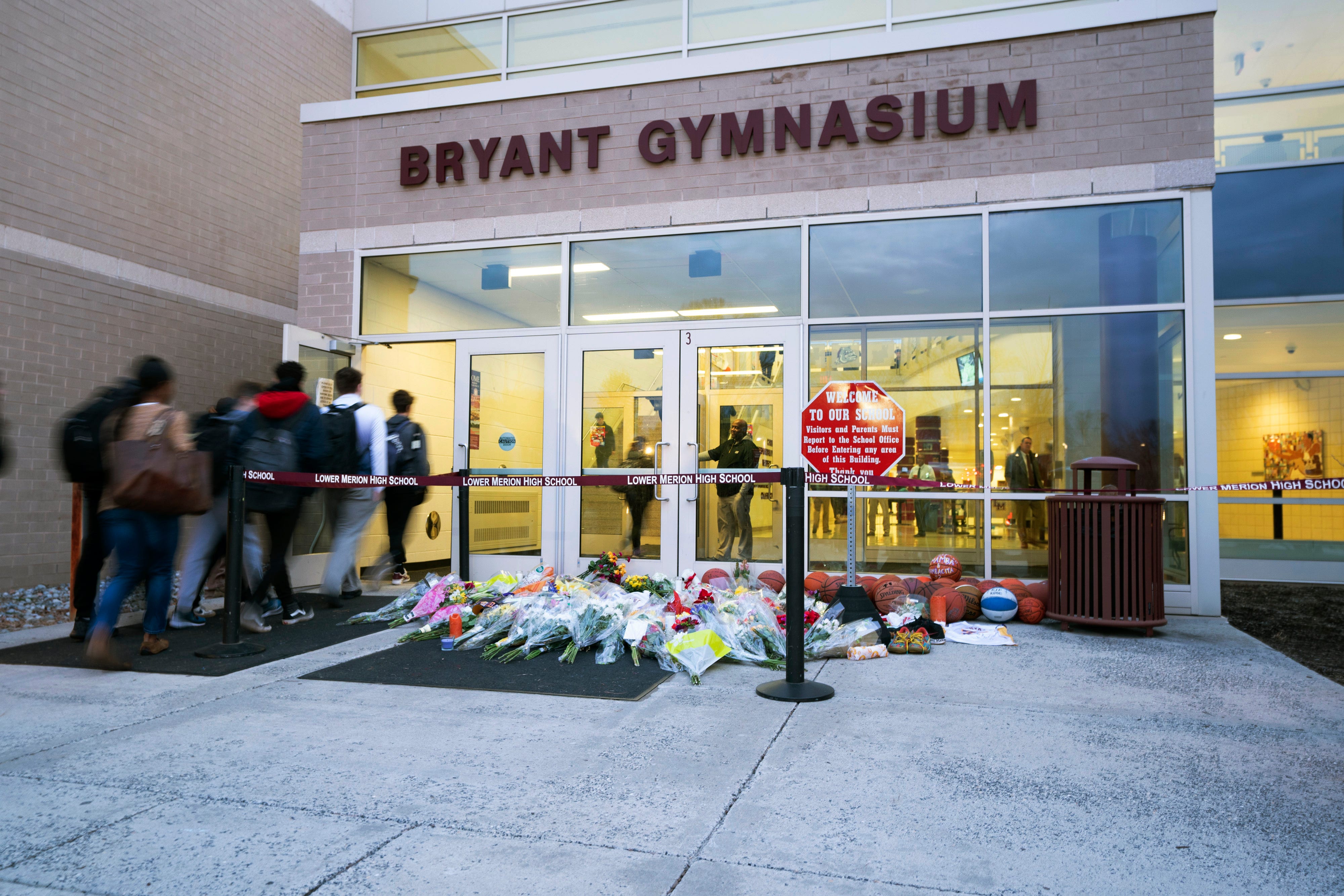 Students walk past the flowers, jerseys and imagery that were left in remembrance to Kobe Bryant at a small memorial at the entrance of the Bryant Gymnasium at Lower Merion High School in Wynnewood, PA.