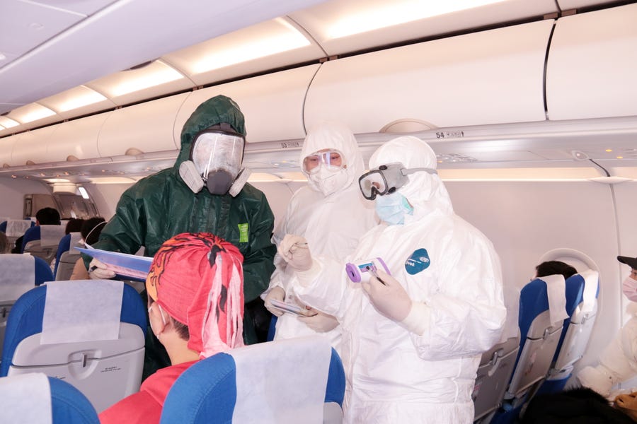 Police and medical personnel take the temperature of airplane passengers Tuesday upon arrival at the airport in Zhoushan City, Zhejiang Province, China.