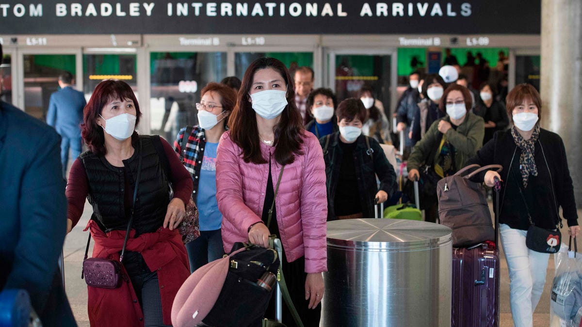 Passengers wear masks to protect against the spread of the Coronavirus as they arrive on a flight from Asia at Los Angeles International Airport on Jan. 29, 2020.