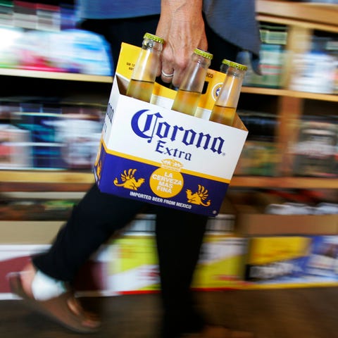 A customer carries a six-pack of Corona beer, a Co