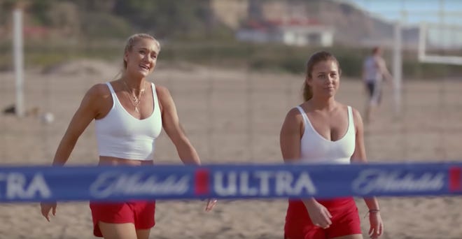 This undated image provided by Michelob ULTRA shows Kerri Walsh Jennings, left, and former FGCU volleyball star Brooke Sweat in a scene from the company's 2020 Super Bowl NFL football spot. Michelob Ultra stresses its low calories and low carbs in an ad that shows talk show host Jimmy Fallon and wrestler John Cena working out.