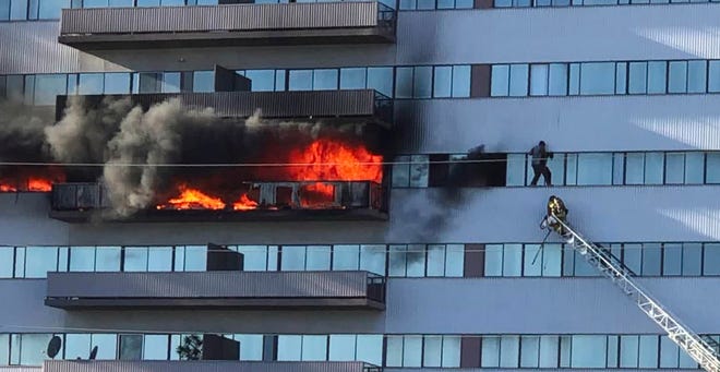 This image from video by Jenna Fabian shows a Los Angeles Fire Department firefighter on a ladder rescuing a man who had climbed out on the side of a 25-story high-rise apartment, escaping flames from a burning apartment balcony on Jan. 29, 2020.