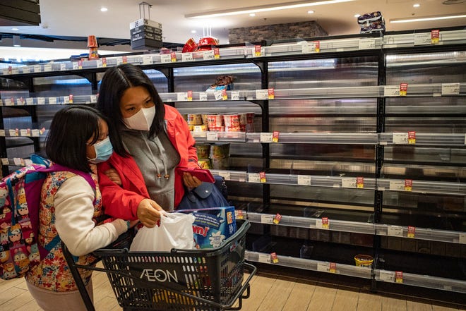 Customers, wary of the spreading coronavirus, wear face masks as they walk past empty shelves in a grocery store on January 31, 2020 in Hong Kong.