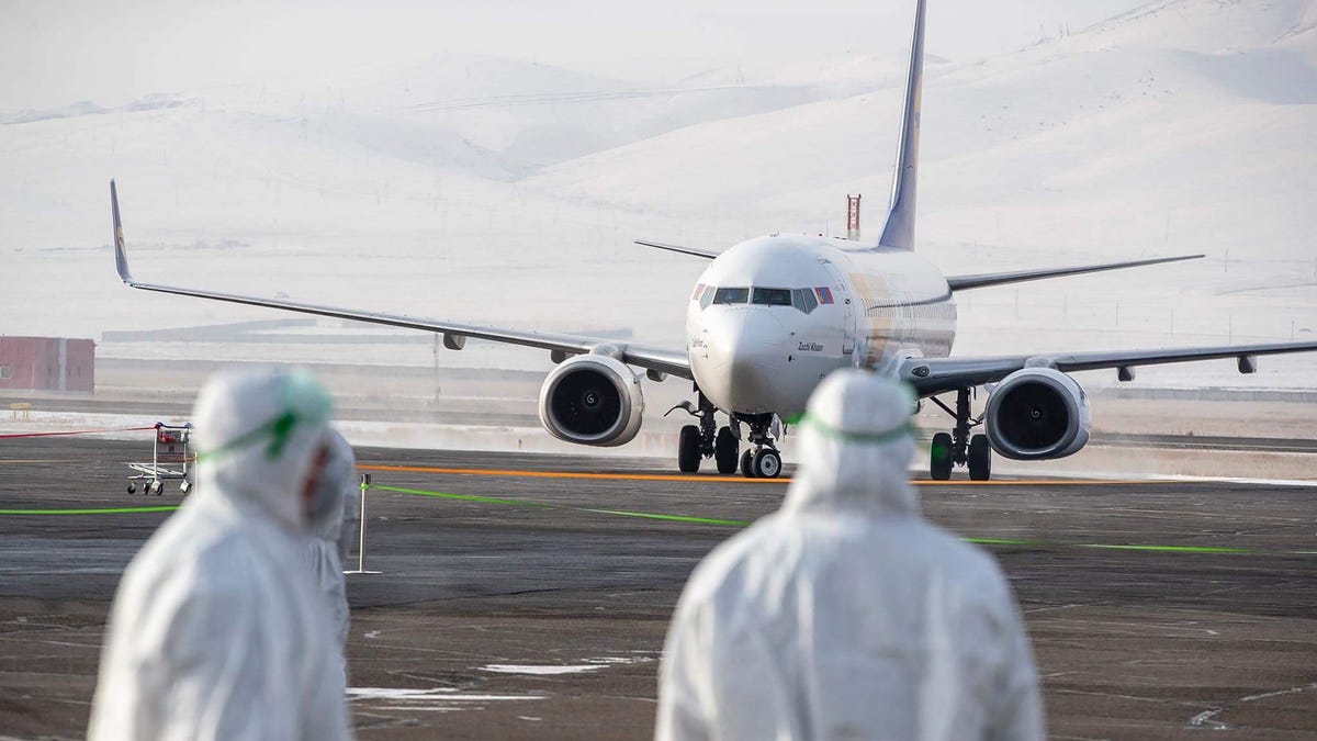 Staff members, wearing protective suits, watch as a plane carrying 32 Mongolian citizens for their evacuation from the Chinese city of Wuhan arrives in Ulaanbaatar, the capital of Mongolia on February 1, 2020. China faced deepening isolation over its coronavirus epidemic on February 1 as the death toll soared to 259, with the United States leading a growing list of nations to impose extraordinary Chinese travel bans.
