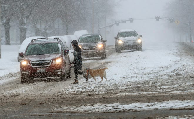 A dog walker crosses the road, Monday, Feb. 3, 2020, in Salt Lake City, Utah, after a winter storm dropped over a foot of snow in parts of the valley.
