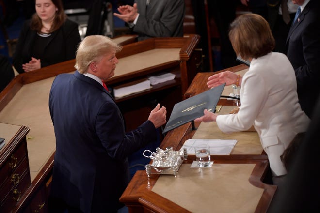 US President Donald Trump passes the written address to Speaker of the House Nancy Pelosi, but does not shake her hand before President Donald J. Trump delivers the State of the Union address from the House chamber of the United States Capitol in Washington. 