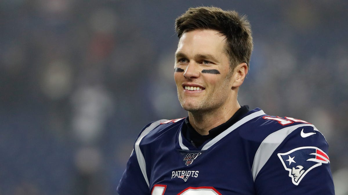 New England Patriots quarterback Tom Brady (12) smiles at teammates before their playoff game against the Tennessee Titans at Gillette Stadium.