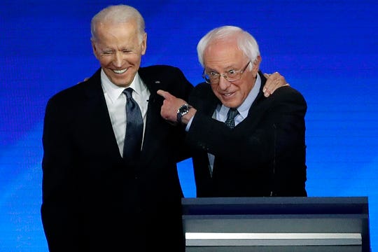 Former Vice President Joe Biden, left, embraces Sen. Bernie Sanders, I-Vt., laugh during a Democratic presidential primary debate.