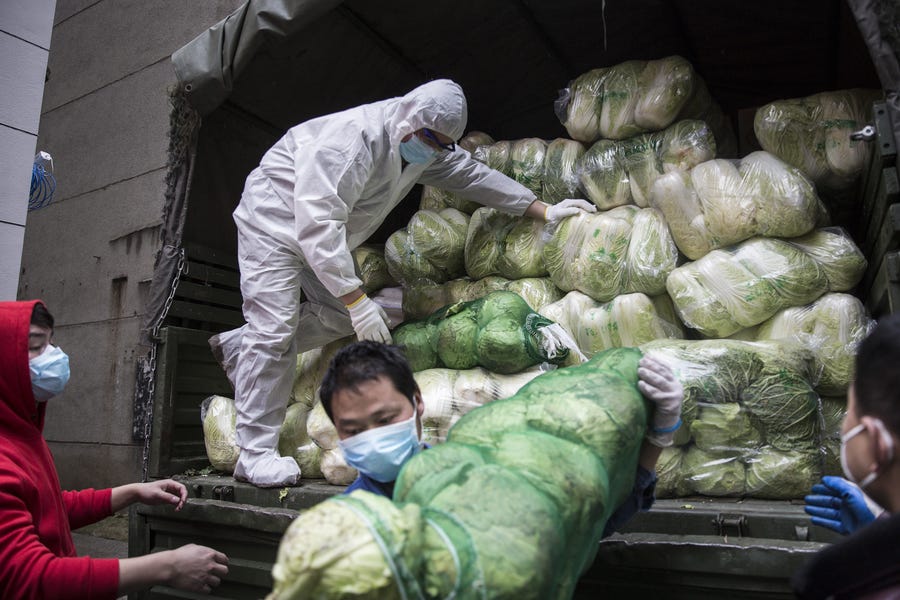 Employees wear protective masks while carrying vegetables from trucks at a hospital on Feb. 10 in Wuhan, China.