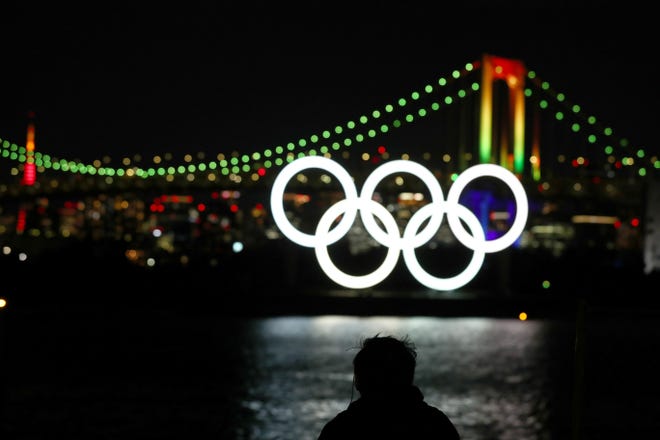 A member of the public looks on as the Olympic rings are illuminated for the first time to mark 6 months to go to the Olympic Games at Odaiba Marine Park on Jan. 24, 2020 in Tokyo, Japan. (Photo by Clive Rose/Getty Images)