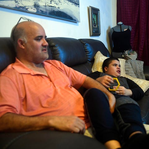Henry Tejada watches TV with his son Carlos, 12, o