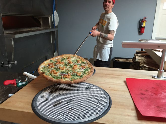 Folino's Pizza employee Bobby Seaman takes a Fire Kracker Shrimp pizza out of the oven at the restaurant in Burlington in 2018.