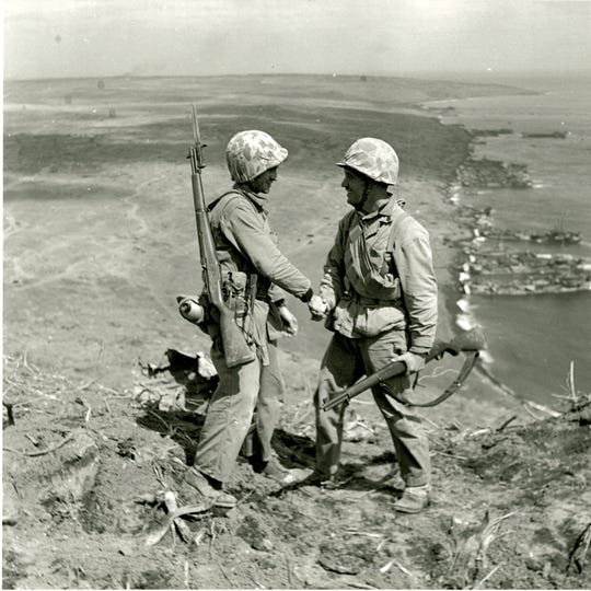 Cpl. Harold "Pie" Keller, right, shakes hands with Sgt. Howard Snyder, left, as they stand on the rim of Mount Suribachi on Iwo Jima between the first and second flag raisings on Feb. 23, 1945. (Official U.S. Army photo, courtesy Pfc. George Burns, George Burns Collection, U.S. Army Heritage and Education Center)