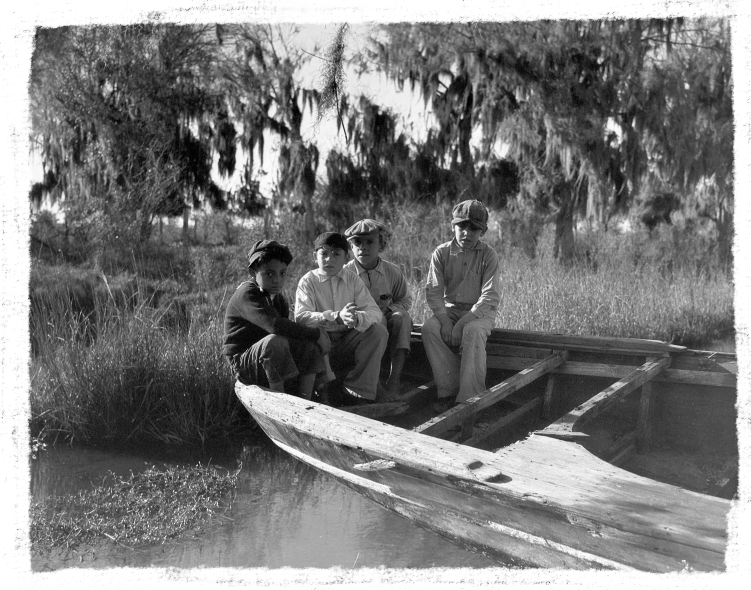 Four boys sit on a pirogue, a flat-bottomed canoe many Isle de Jean Charles residents used to get to the mainland before Island Road was built in 1953.