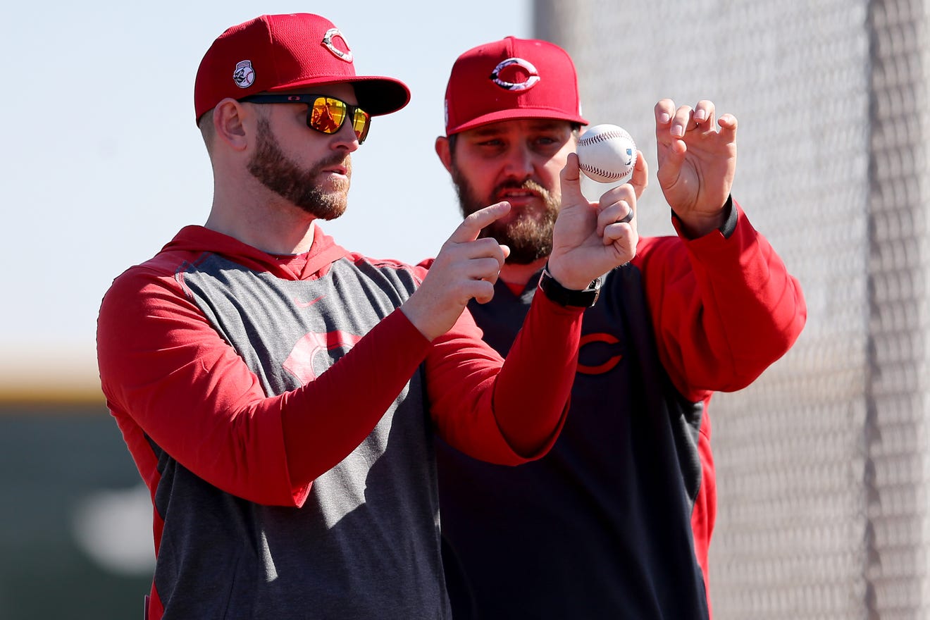 Cincinnati Reds assistant pitcher coach Caleb Cotham, left, works with Cincinnati Reds pitcher Wade Miley (22), right, Saturday, Feb. 15, 2020, at the Cincinnati Reds Spring Training Facility in Goodyear, Arizona.
