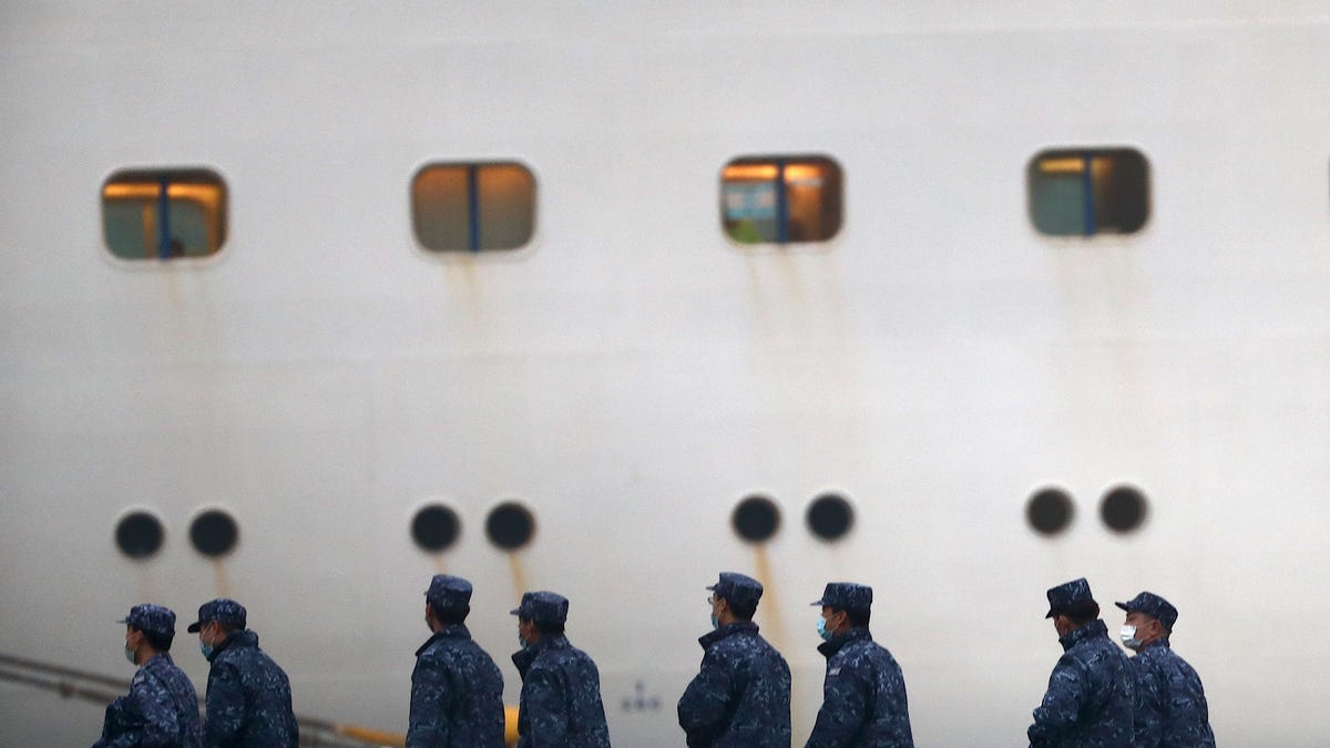 Japan Self-Defense Forces walk past the Diamond Princess cruise ship, with people quarantined onboard due to fears of the new coronavirus, at the Daikaku Pier Cruise Terminal in Yokohama port on Feb. 16, 2020. The number of people who have tested positive for the new coronavirus on a quarantined ship off Japan's coast has risen to 355, the country's health minister said.