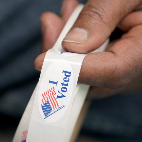 Poll worker Charles Hawkins holds "I Voted" sticke