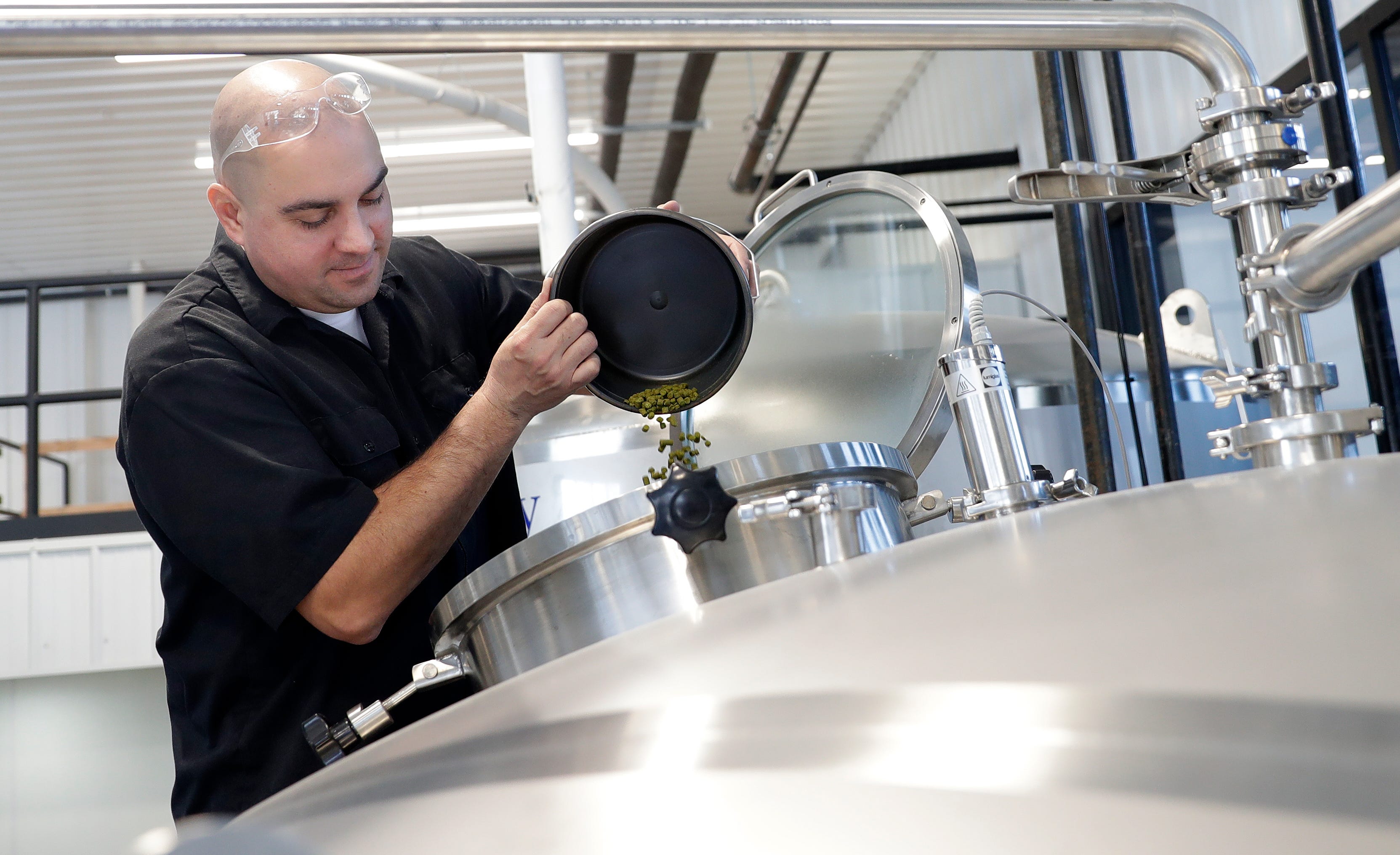 David Malcolm, co-owner of Zambaldi Beer, pours hops into a brewing tank while making his first batch of beer on Feb. 14 at the newly opened Allouez brewery and taproom.