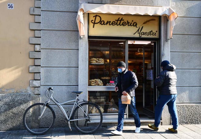 A customer wearing a protective respiratory mask leaves a bakery in Codogno, southeast of Milan. A dozen towns are locked down in the region following the first two coronavirus deaths in Italy.