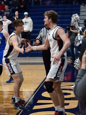 Carver Myers, of Morgan, is congratulated by teammate Gabe Altier after scoring his 1,000th career point on a layup in the third quarter. The Raiders won their Division III sectional opener against Buckeye Trail, 69-50.