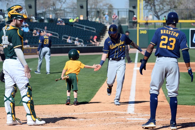 Brewers third baseman Lucas Erceg slaps hands with a bat boy as Erceg approaches home plate after hitting a two-run home run against the Oakland Athletics during the second inning of a spring training game at HohoKam Stadium.