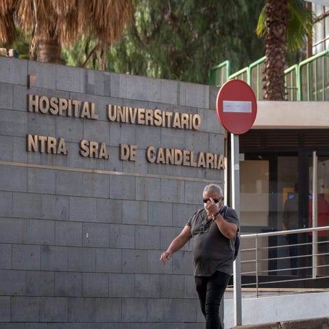 A man wearing a mask walks past the University Hos