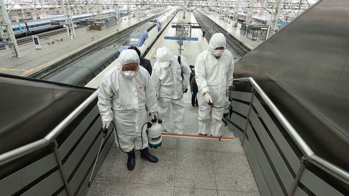 Workers wearing protective gears spray disinfectant as a precaution against the new coronavirus at Seoul Railway Station in Seoul, South Korea, Feb. 25, 2020.