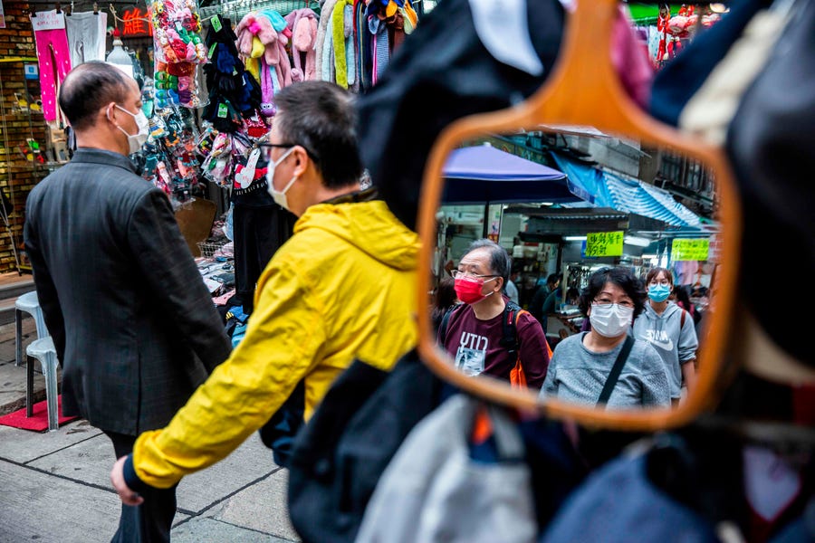 People wearing protective face masks walk through a market in the wan chai district of Hong Kong on February 25, 2020. The new coronavirus has peaked in China but could still grow into a pandemic, the World Health Organization warned, as infections mushroom in other countries.