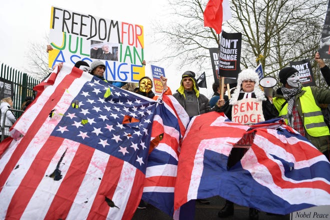 Supporters of WikiLeaks founder Julian Assange hold U.S. and U.K. flags and placards calling for his freedom outside Woolwich Crown Court in southeast London on Feb. 24, 2020.