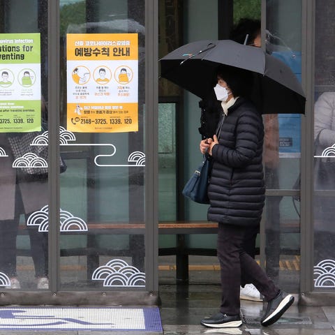 A woman wearing face mask passes by posters about 