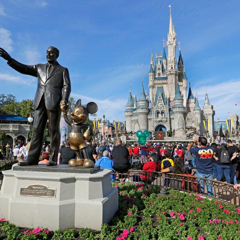 Guests watch a show near a statue of Walt Disney a
