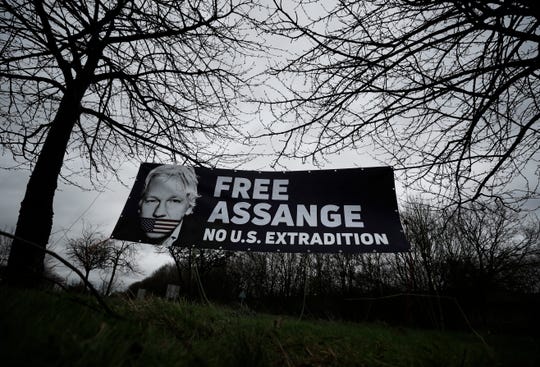 A banner put up by supporters, against the extradition of Wikileaks founder Julian Assange, hangs between trees outside a court in London, on Feb. 24, 2020.