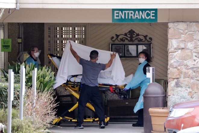 A person is taken by stretcher to a waiting ambulance from a nursing facility where more than 50 people are sick and being tested for the COVID-19 virus, Saturday, Feb. 29, 2020, in Kirkland, Wash.