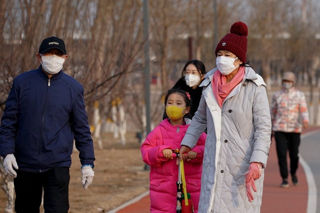 People wear face masks during a visit to a park in Beijing on February 29, 2020.